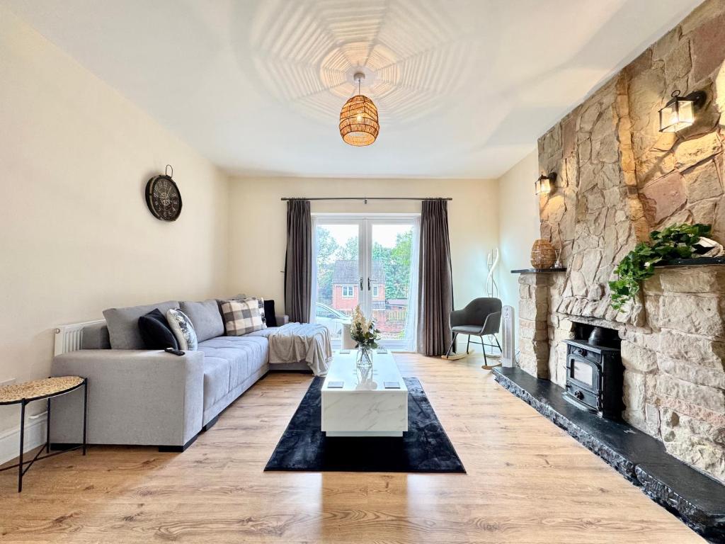 Una sala de estar con un sofá y una chimenea de piedra. en Spacious 6 Bedroom Home with Pool Table - Free Driveway Parking - 12 beds and 3 Bathrooms - Rustic Cottage Features, en Teversall