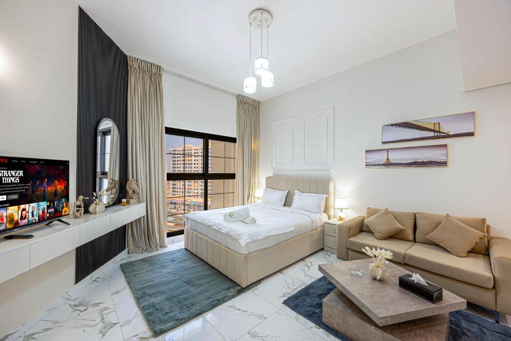a bedroom with a bed and a couch and a tv at Comfortable Studio with Dubailand Vibes in Dubai