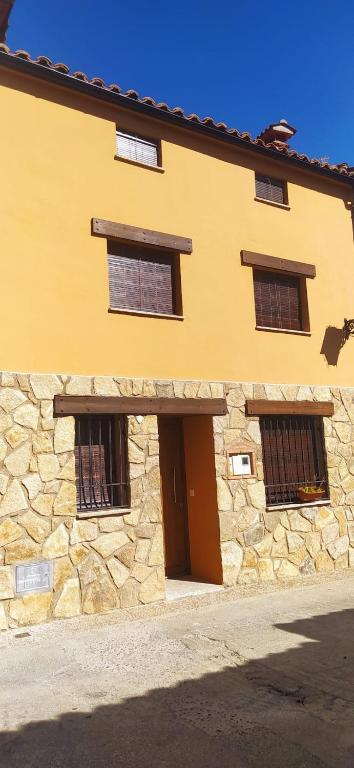ein Steingebäude mit drei Fenstern und einer Tür in der Unterkunft Casa Misi in Candeleda
