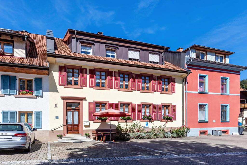 a building with red shutters and a car parked in front at Haus Am Bühl in Schönau im Schwarzwald