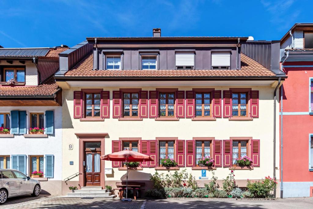 a building with red shuttered windows and an umbrella at Haus Am Bühl in Schönau im Schwarzwald