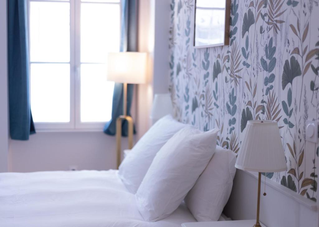 une chambre avec un lit avec des oreillers blancs et une fenêtre dans l'établissement Havre de paix - au cœur de Paris, à Paris