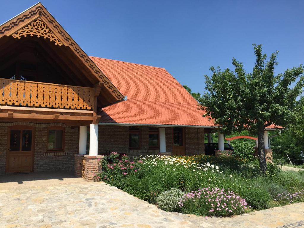 ein Haus mit einem orangenen Dach und einem Garten mit Blumen in der Unterkunft Napfenyes Vendeghaz in Bükkösd