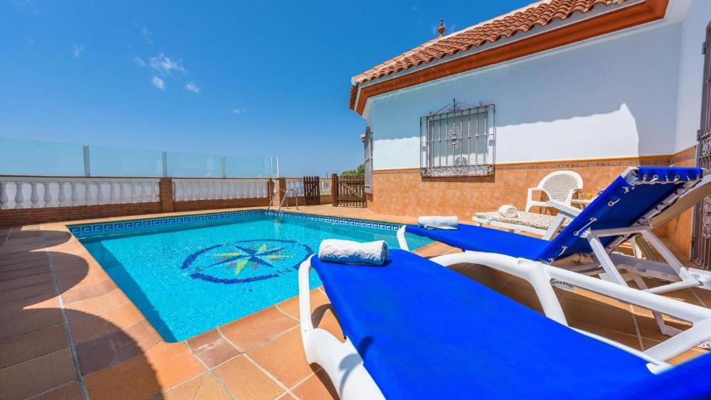 a villa with a swimming pool and two blue chairs at Castillo de la Hazalara Cómpeta by Ruralidays in Cómpeta