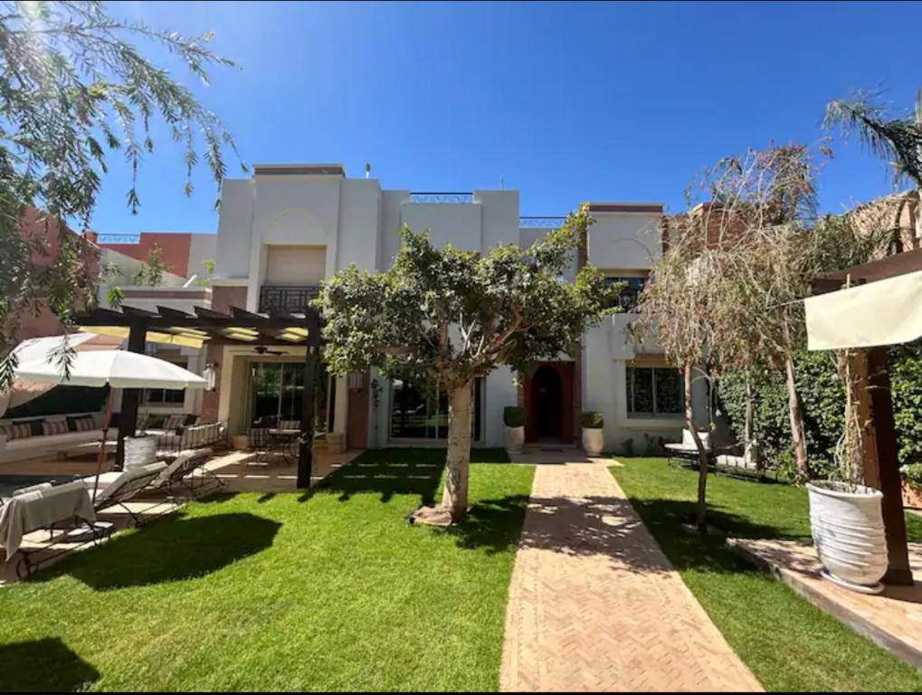 une maison avec une cour avec de l'herbe et des arbres dans l'établissement Villa golf amelkis Marrakech, à Sfiani