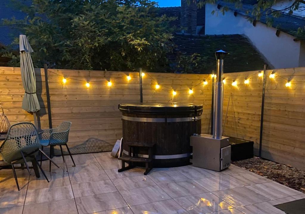 Un patio con jacuzzi y luces en una cerca. en Chalet bain nordique - Calm & relax, en Bellême