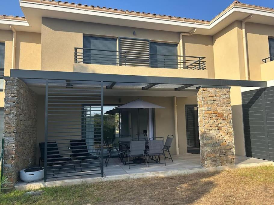 Cette maison dispose d'une terrasse avec des chaises et un parasol. dans l'établissement villa 2 au Clos d Alice, à Sainte-Maxime