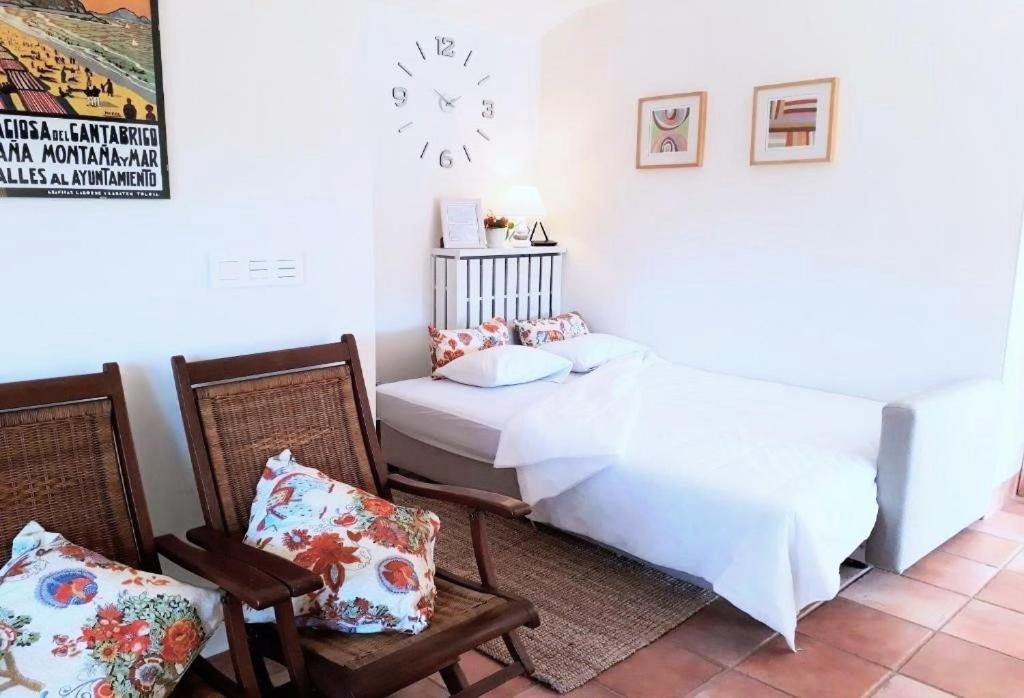 sypialnia z łóżkiem, 2 krzesłami i zegarem w obiekcie alaia apartamento w mieście Zarautz