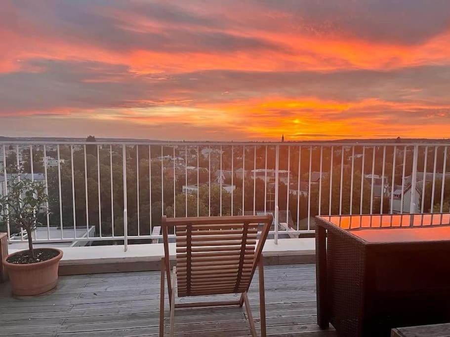 un coucher de soleil sur un balcon avec une table et une chaise dans l'établissement Le Captivant - À Versailles - 17MB, à Versailles