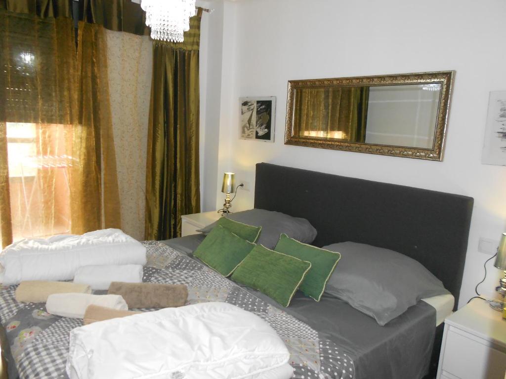 a bedroom with a bed with green pillows and a mirror at Jardinas de les Marinas in Denia