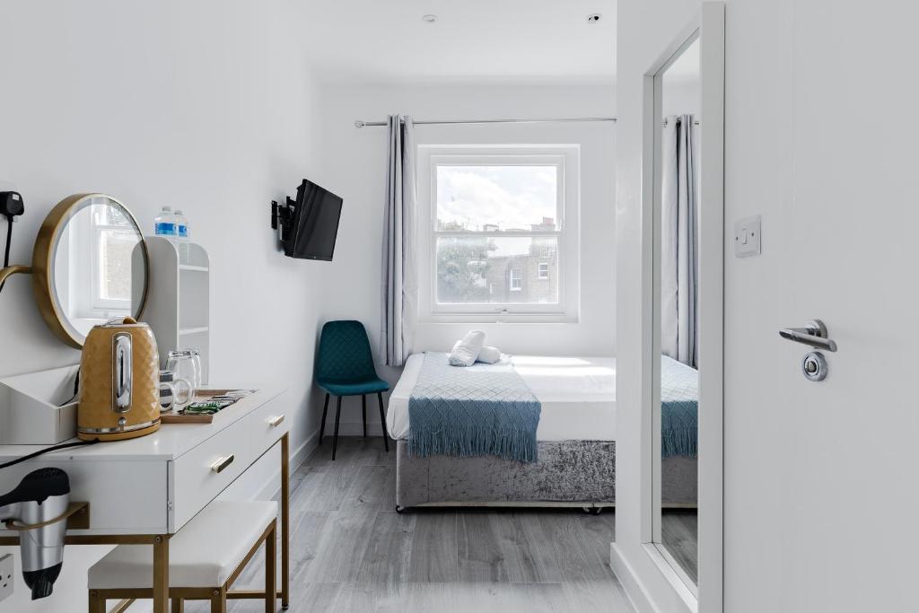 a white room with a bed and a window at Wembar Hotel in London