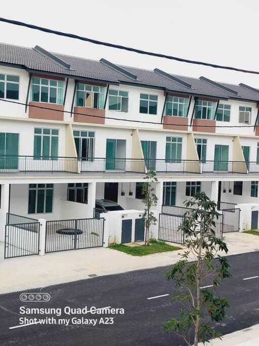 a large white building with green windows and a street at Azzahra Homestay Scientex Kundang Jaya in Rawang