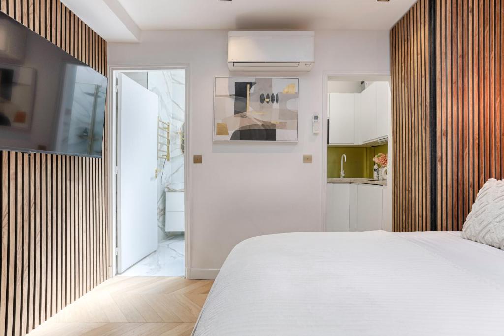 Cet appartement comprend une chambre avec un lit blanc et une cuisine. dans l'établissement Charming Pied à Terre near Montmartre, à Paris
