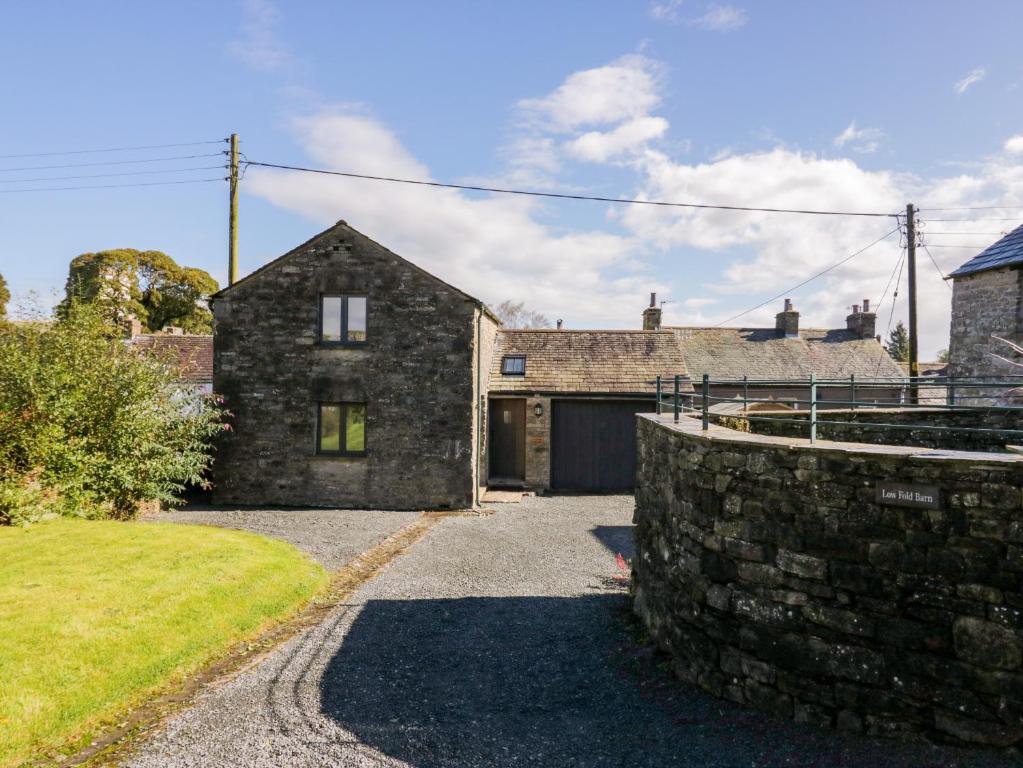 a stone house with a garage and a stone wall at Low Fold Cottage in Penrith