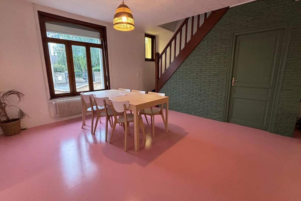 a table and chairs in a room with a pink floor at Grande Maison 17 personnes in Arras
