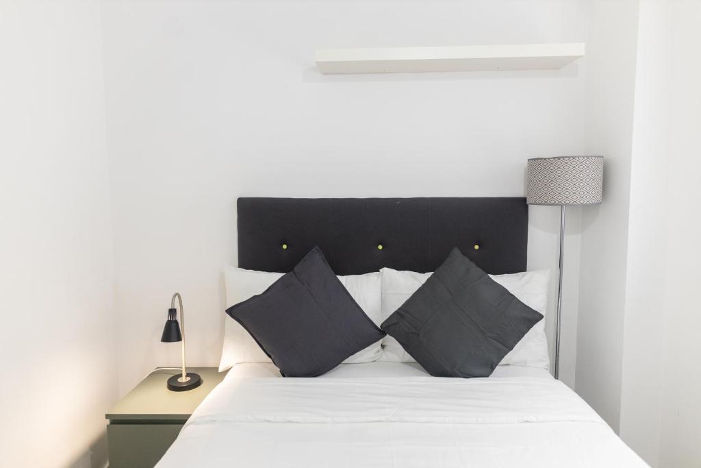 - une chambre avec un lit blanc et des oreillers noirs dans l'établissement Leeds City Centre New Apartment, à Leeds