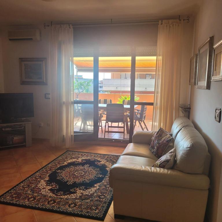 a living room with a couch and a view of a patio at Alloggio per uso turistico ECM Giardino di Roma in Vitinia