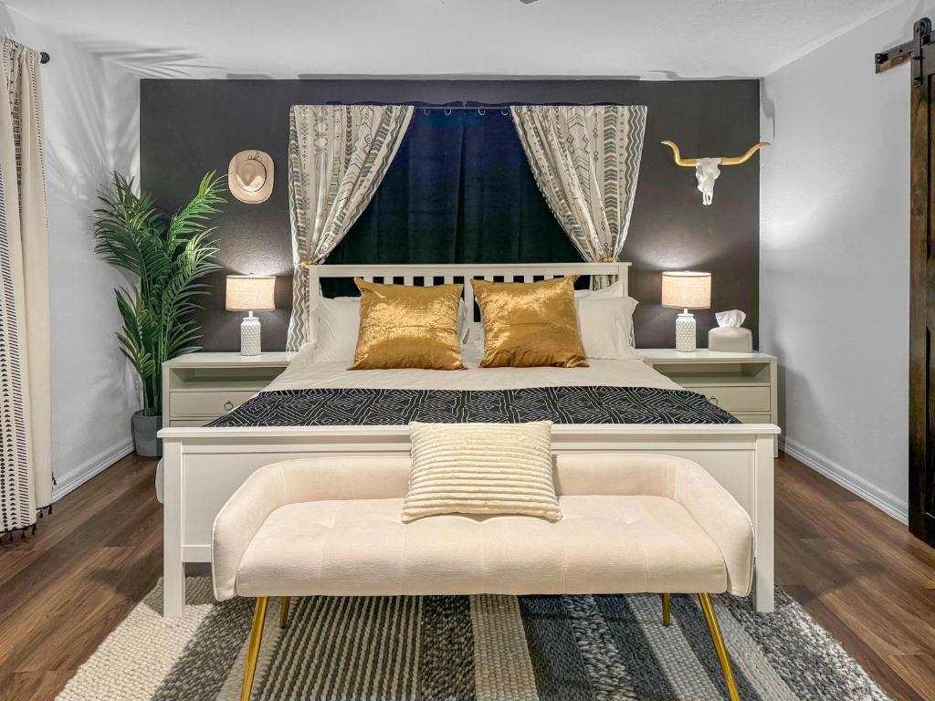 a bedroom with a large white bed with gold pillows at Casa Hosum - 7 mins Downtown Sleeps 9 King Bed Fenced Yard in Houston