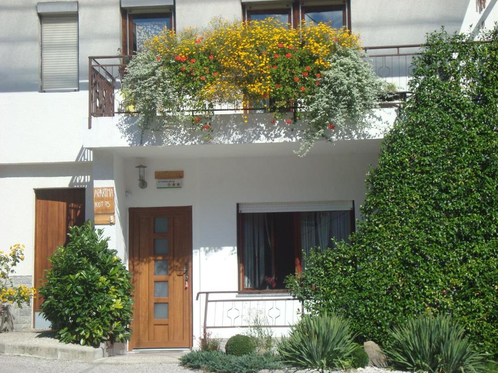 Biały budynek z drzwiami i kwiatami w obiekcie Apartment Norma w mieście Bovec