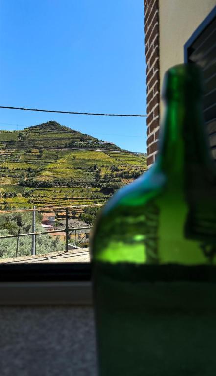 a green bottle in a window with a view of a hill at Sobreira Stone Cottage in Peso da Régua