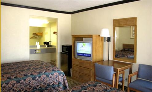 Habitación de hotel con cama, escritorio y TV. en Town House Motel, en Chico