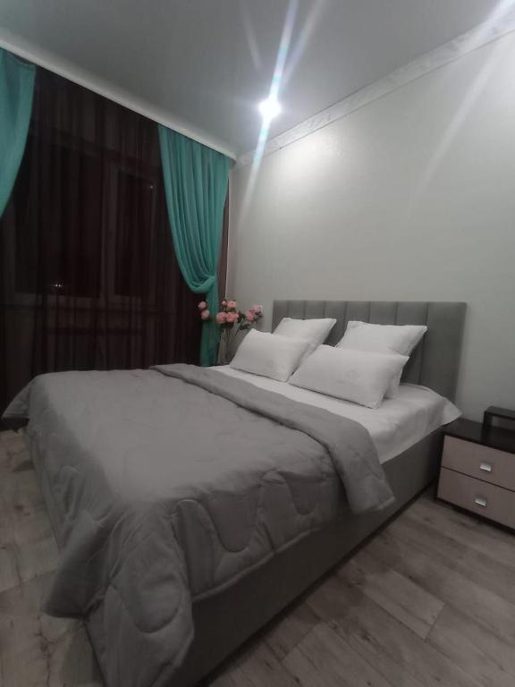 a large bed in a bedroom with green curtains at VIP 5 Квартира 2ком in Oral