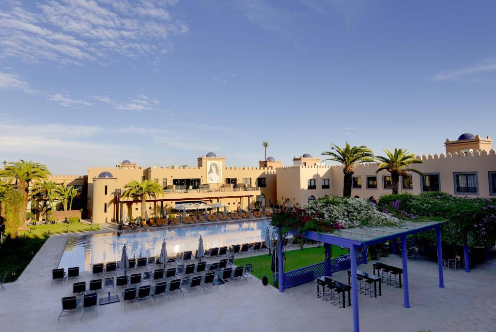 un complejo con mesas y sillas y un edificio en Adam Park Marrakech Hotel & Spa, en Marrakech