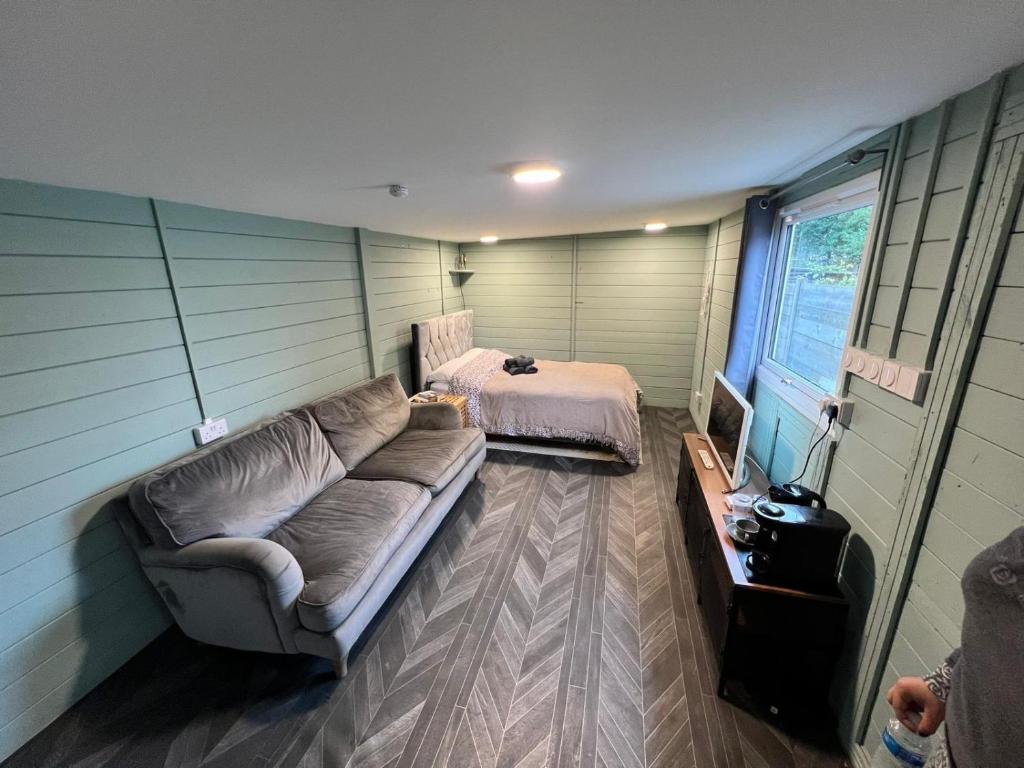 a living room with a couch and a bed at Cozy cabin independent ensuite in Guildford