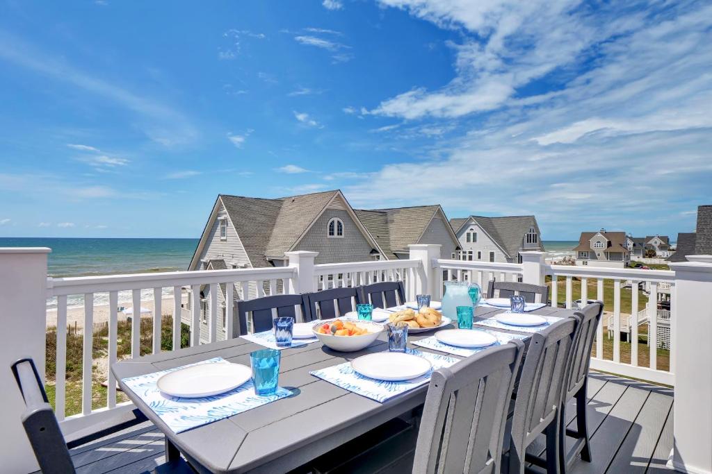 a table on a balcony with a view of the ocean at Grand Topsail Villa by Sea Scape Properties in North Topsail Beach