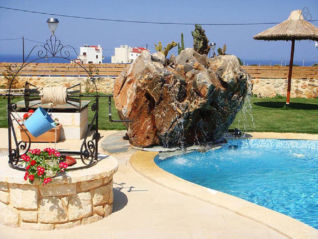 a swimming pool with a rock fountain in a yard at Villa Valentine in Hersonissos