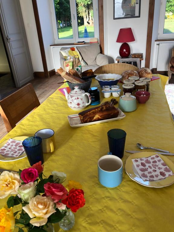 żółty stół z jedzeniem i kwiatami w obiekcie La Maison du Hommeel w mieście Gratot