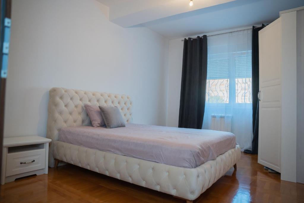 une chambre avec un grand lit blanc avec une grande fenêtre dans l'établissement Biser apartman, à Belgrade