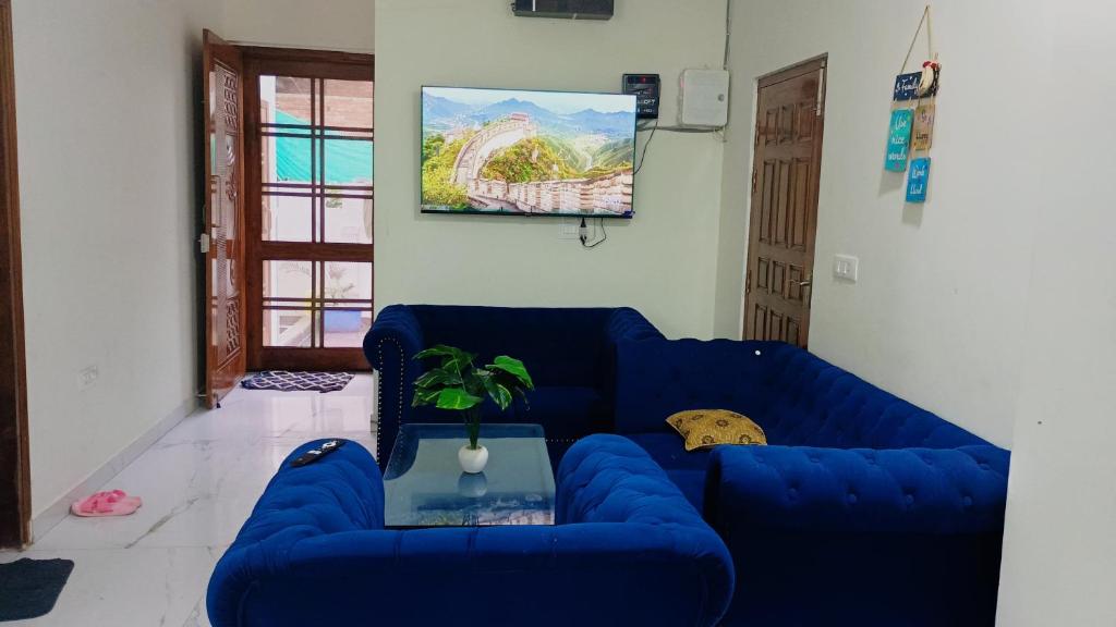 a living room with a blue couch and a table at Five BHK Abode in Golf City Lucknow in Nalmatha