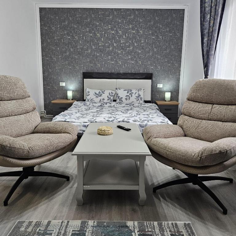 a bedroom with a bed and two chairs and a table at Garsoniera Delia in Braşov