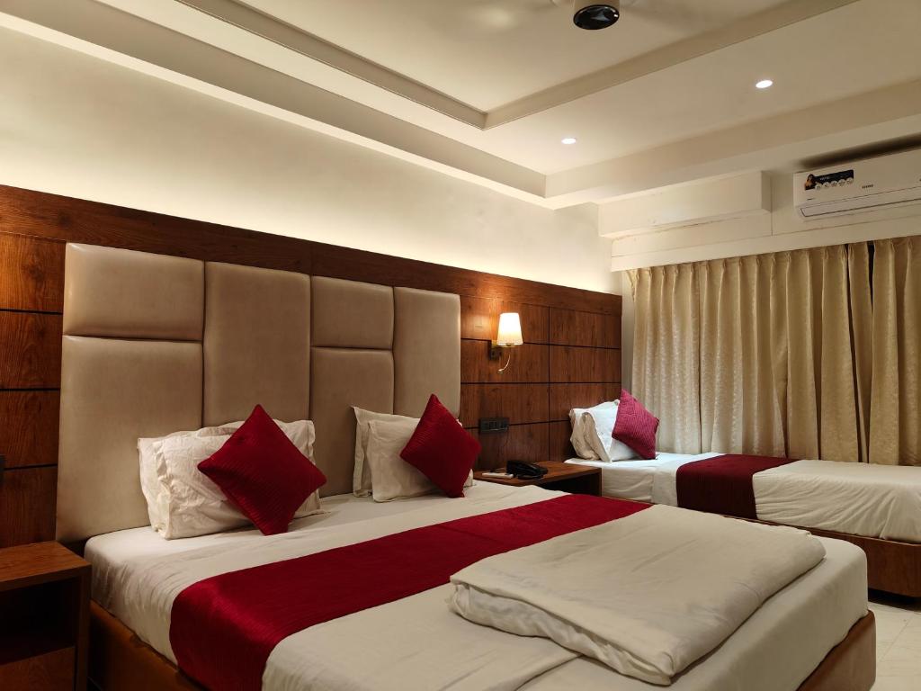 a hotel room with two beds with red pillows at Hotel Anand Palace in Shirdi