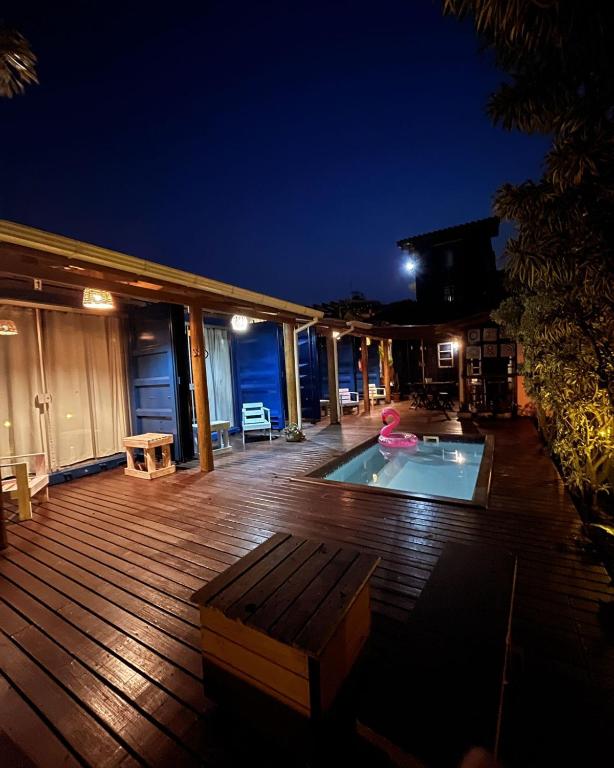 a wooden deck with a swimming pool at night at Capim Limão Containers do Rosa in Praia do Rosa