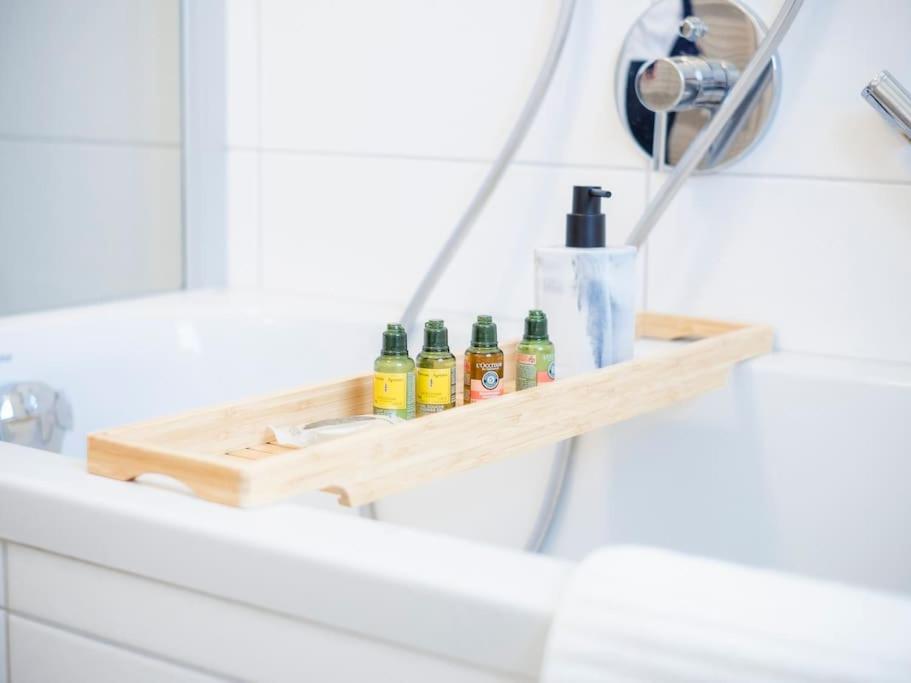 a wooden shelf on a bathroom sink with four bottles at 4-Zimmer-Apartment - Messe - Airport - Tiefgarage - 3-Schlafzimmer - Küche in Leinfelden-Echterdingen