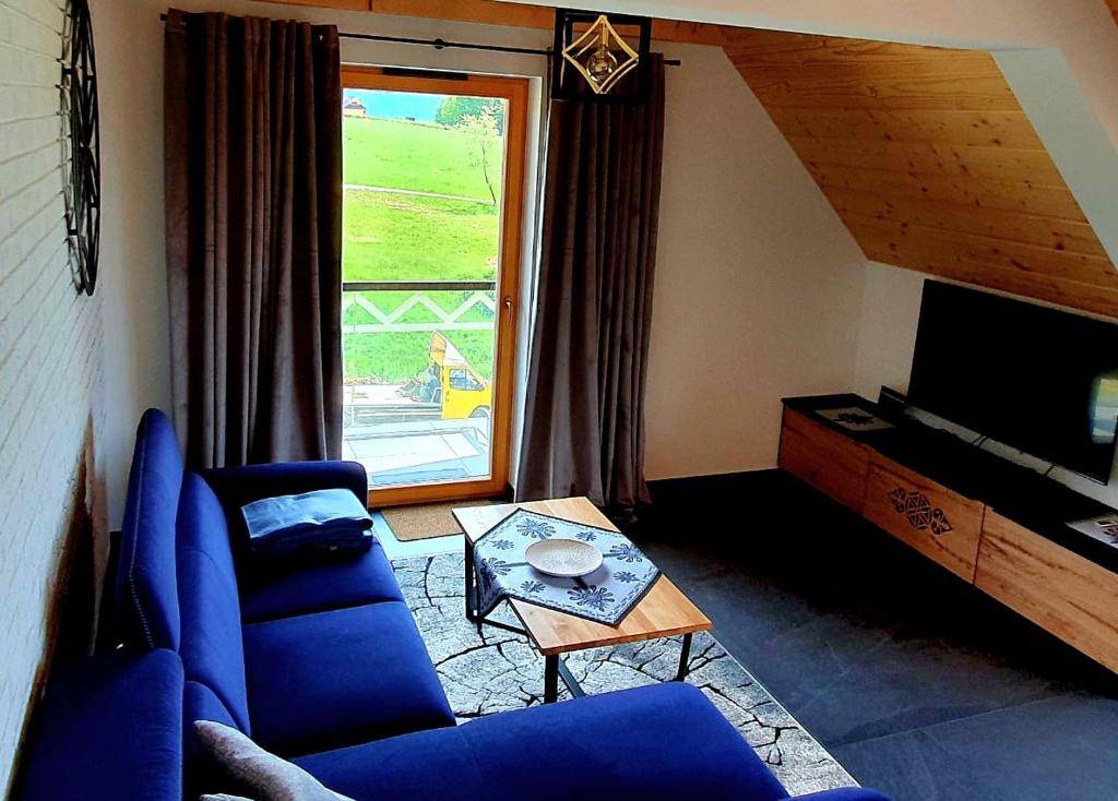 a living room with blue furniture and a large window at Luxury apartment with sauna and garden on the Czorsztyn lake in Kluszkowce