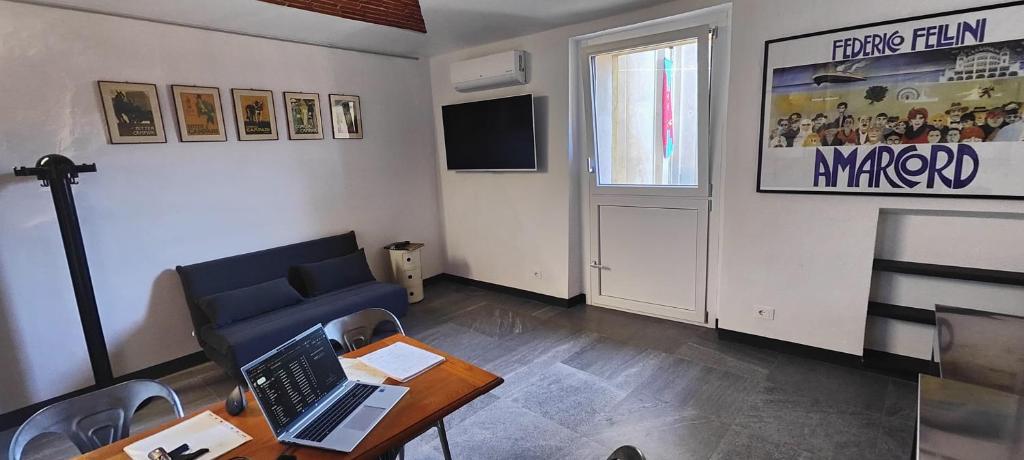 Una sala de estar con un sofá y una mesa con una computadora portátil. en Casa del Mercante in centro ad Asti no ztl, en Asti