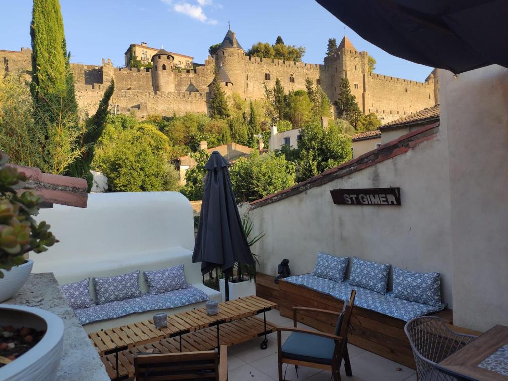 un patio avec des chaises et un parasol ainsi qu'un château dans l'établissement Le Belvédère St Gimer, à Carcassonne
