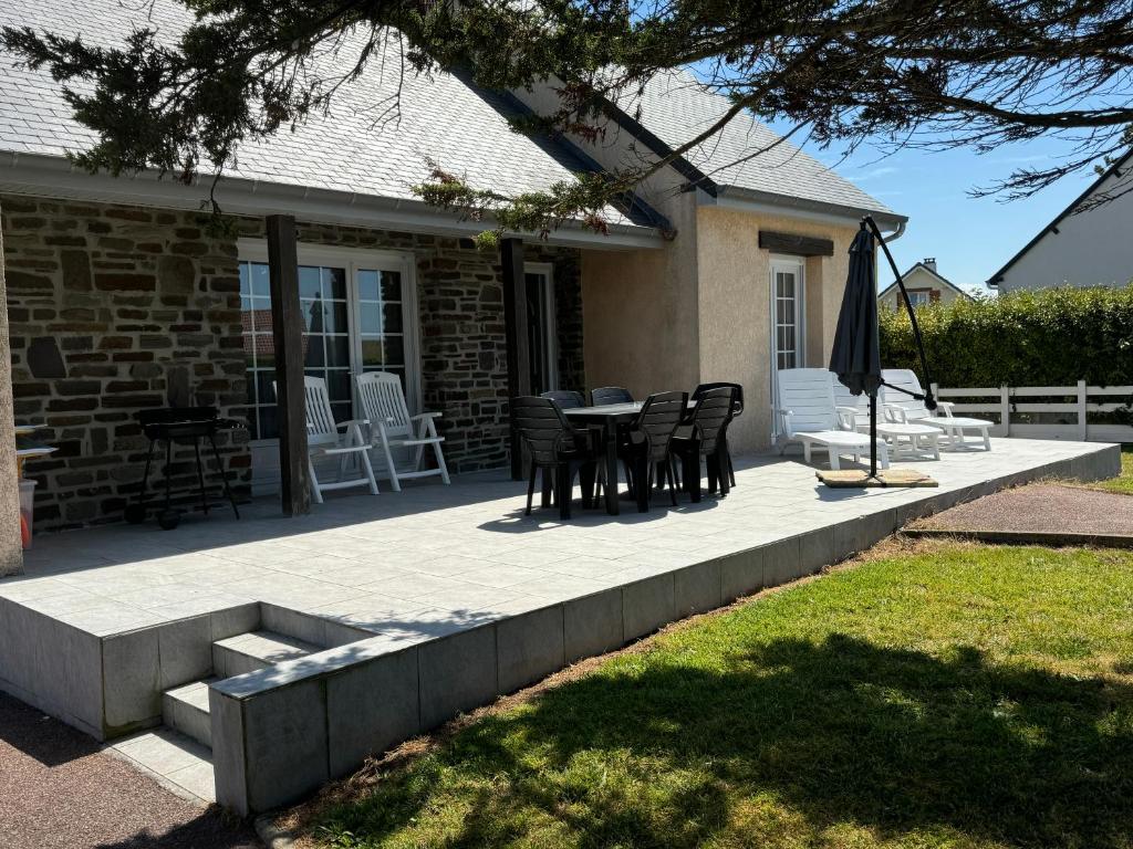 une terrasse avec une table et des chaises dans une maison dans l'établissement Maison La Dune, à Gouville-sur-Mer