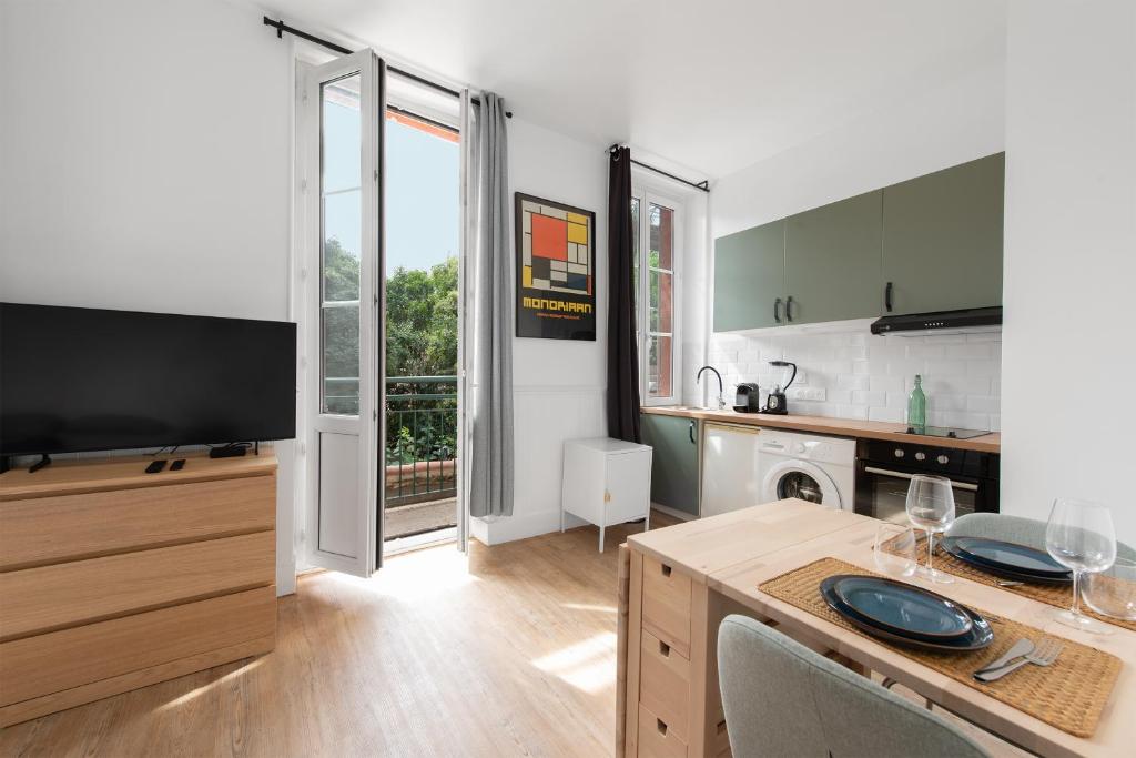 une cuisine avec une télévision et une table avec des chaises dans l'établissement Le verdoyant - studio au coeur de Toulouse, à Toulouse