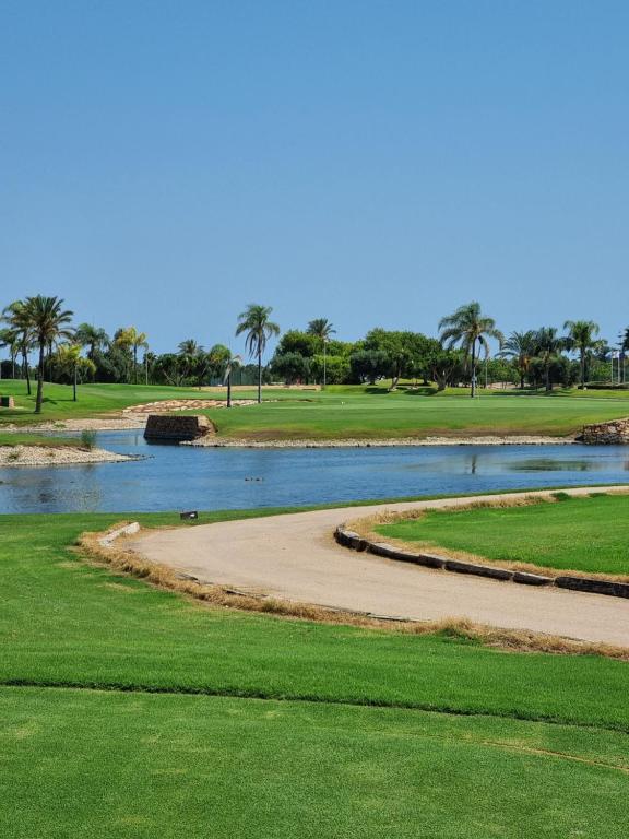 un campo da golf con un fiume e palme di Casa Verano in Roda Golf and Beach Resort Mar Menor a San Javier