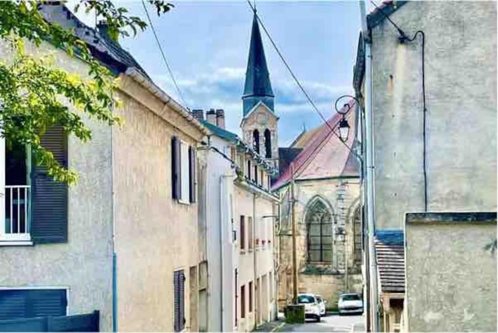 un vieux bâtiment avec une église et une rue avec des voitures dans l'établissement Apt 5 Dammartin, à Dammartin-en-Goële