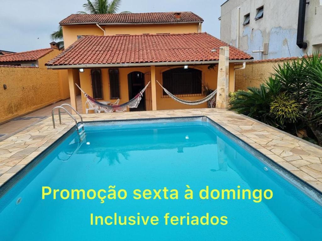 a villa with a swimming pool and a house at Casa com piscina in Bertioga