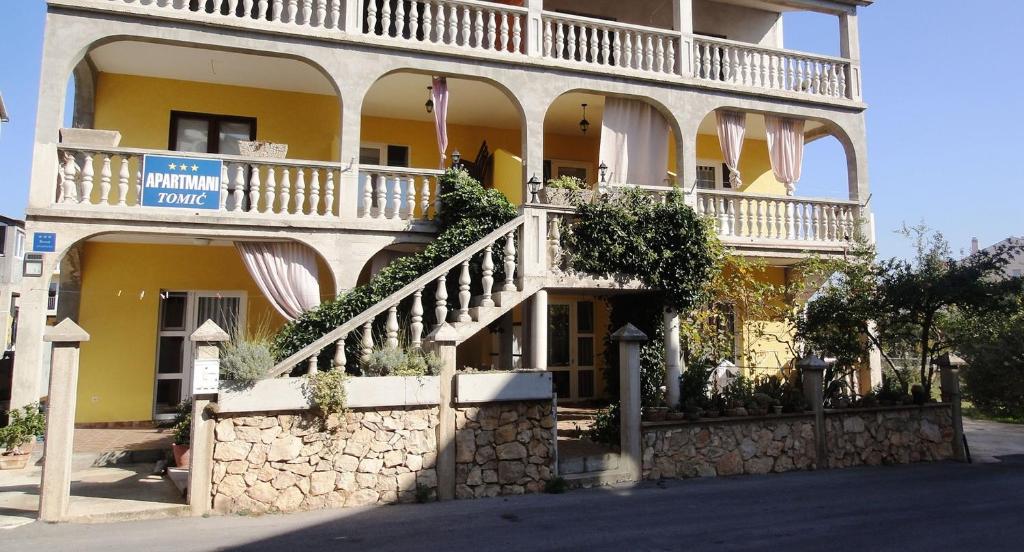 a large yellow building with stairs and plants on it at Apartments Tomić in Vodice