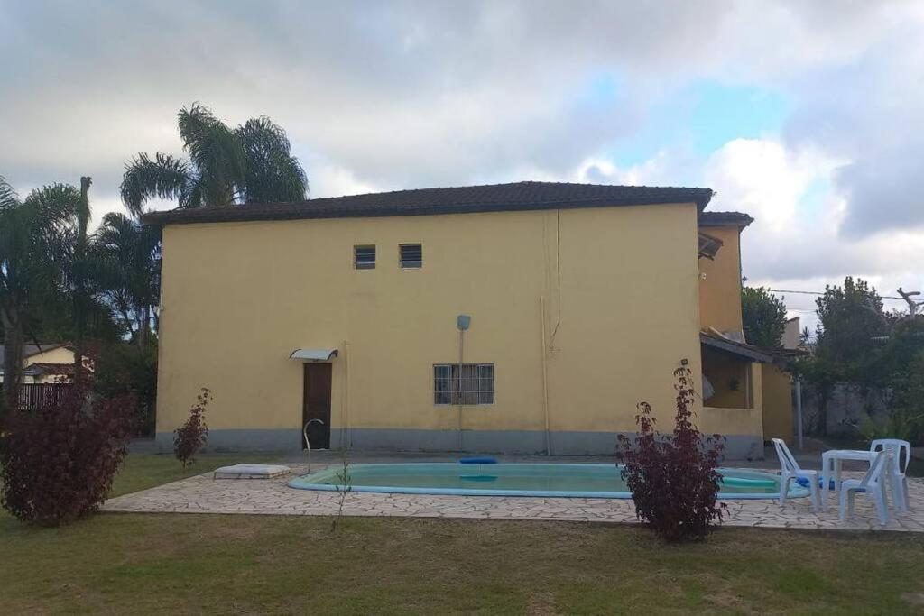 a building with a pool in front of a house at Canto Verde casa de veraneio, férias e piscina in Cananéia