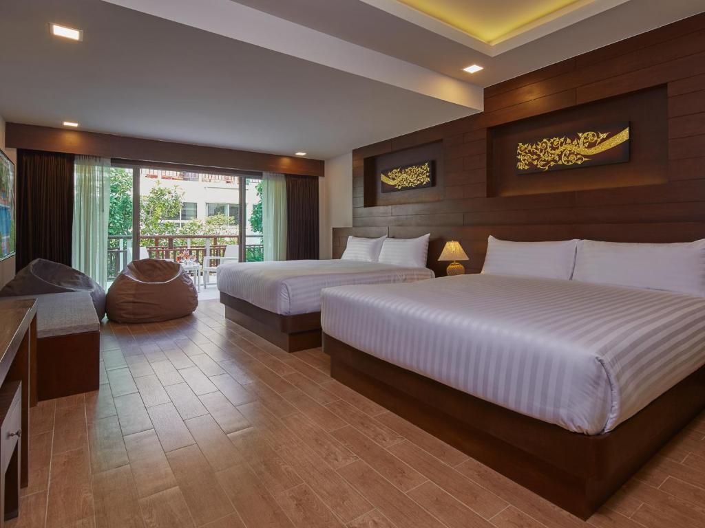 a hotel room with two beds and a television at The Agate Pattaya Boutique Resort in Pattaya South