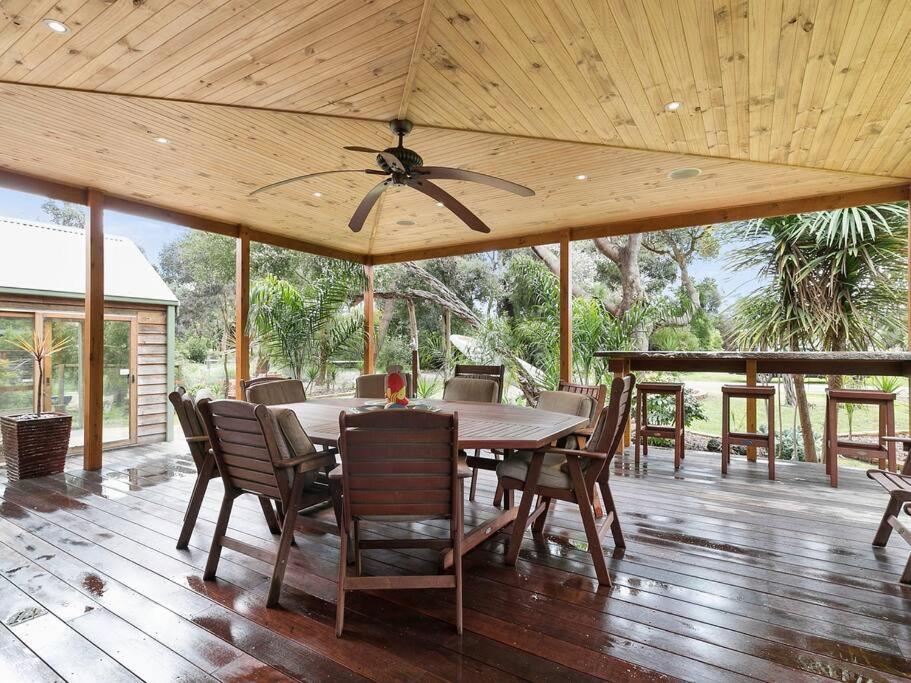 a dining room with a table and chairs on a deck at Silverleaves on the Beach in Rhyll
