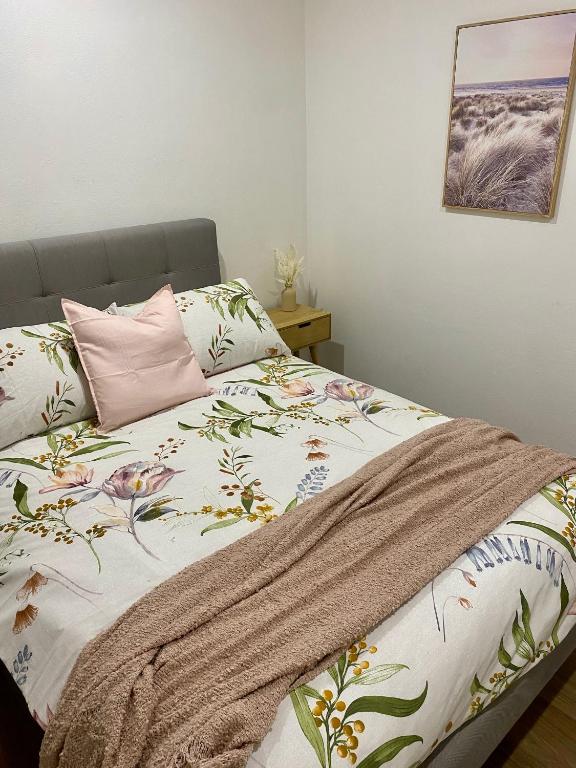 a bed with a blanket and a pink pillow at Modern Stylish House in Craigie in Perth